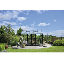 Gewächshaus im Garten mit Pflanzen und Gartenmöbeln