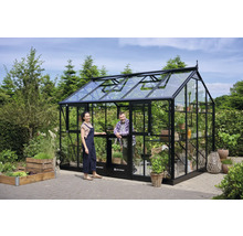 Gewächshaus aus Glas und Metall mit zwei Personen im Garten.