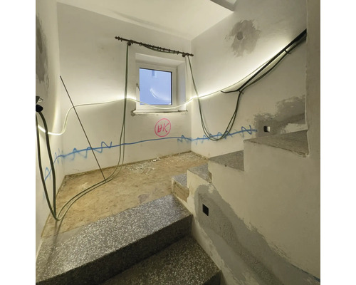 Treppenhaus mit Treppe, Fenster, Wanddekoration und elektrischen Leitungen