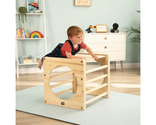Kind beim Spielen mit einem Klettergerüst aus Holz im Kinderzimmer.