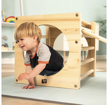 Kind klettert durch einen Holzspielwürfel mit Sprossen und einer Rutsche im Kinderzimmer.