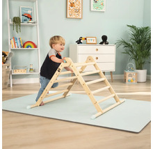 Kind klettert auf einem Indoor-Klettergerüst aus Holz auf einer Spielmatte im Kinderzimmer.