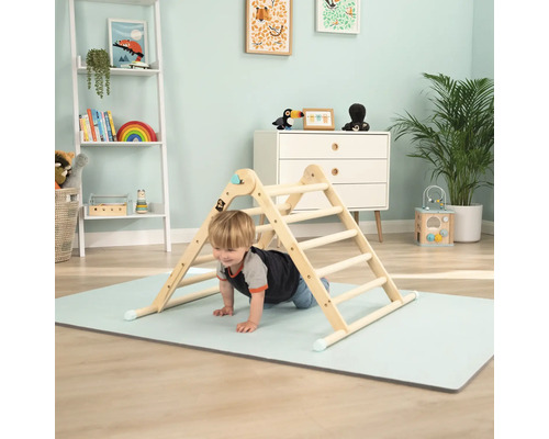 Kind klettert auf einem hölzernen Klettergerüst in einem hellen Kinderzimmer.