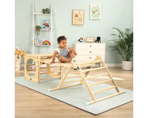 Kleinkind sitzt auf einem hölzernen Klettergerüst im Kinderzimmer.