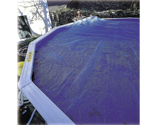 Frau, die eine Solarplane auf einem Pool ausbreitet