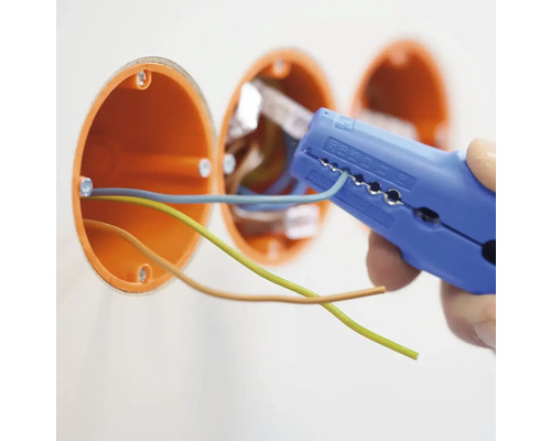 Elektriker entfernt die Isolierung von einem Kabel mit einer Abisolierzange in der Nähe einer Verteilerdose.