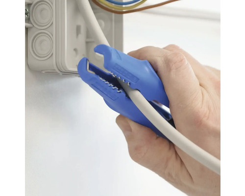 Eine Person verwendet eine blaue Abisolierzange, um ein Kabel neben einer Verteilerdose zu bearbeiten.