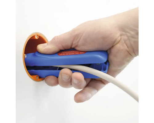 Eine Hand benutzt eine blaue Abisolierzange an einem Kabel in einer Installationsdose.