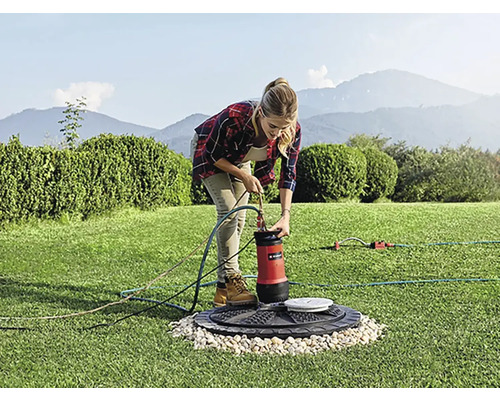 Frau schließt Tauchpumpe im Garten an