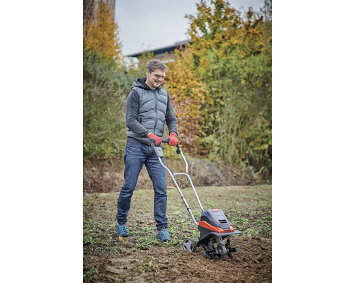 Mann benutzt eine Motorhacke zur Bodenbearbeitung im Garten.