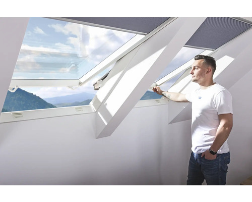 Mann öffnet ein Dachfenster mit Außenansicht