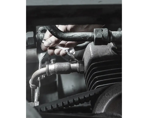 Hand mit Schraubenschlüssel an einer Maschinenkomponente