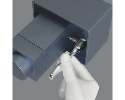 Eine Hand mit einem Schraubenschlüssel schraubt eine Schraube fest.