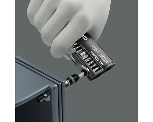 Hand mit Schutzhandschuh benutzt einen Bit-Check Schraubendreher an einem Bolzen.