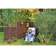 Gartenszene mit Weiden Sichtschutz, Liegestuhl und bepflanzten Blumentöpfen auf einer Rasenfläche