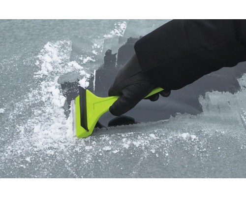 Eine Person entfernt Eis mit einem Eiskratzer von einer Windschutzscheibe.