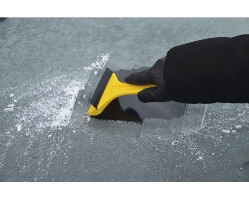 Person entfernt Eis mit einem Eiskratzer von einer Windschutzscheibe.