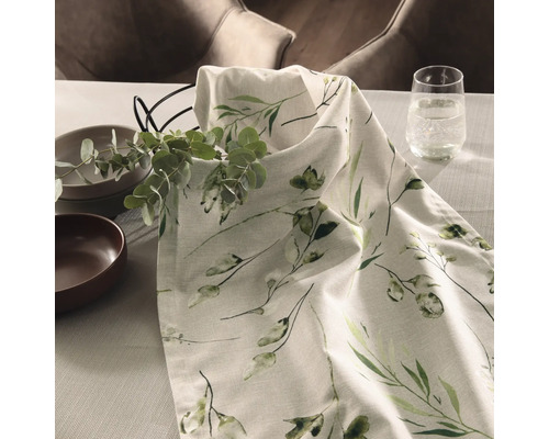 Dekorativer Tisch mit Geschirr, Glas Wasser und Tischdecke mit Pflanzenmuster