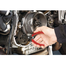 Eine Person verwendet eine Sprengringzange von Knipex an einem Motorradmotor.