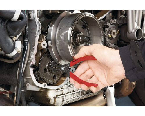 Eine Person verwendet eine Sprengringzange von Knipex an einem Motorradmotor.