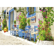 Helle Gasse mit blau gestrichenen Stühlen, Tischen und Pflanzenkübeln vor einer weißen Hauswand