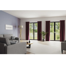 Wohnzimmer mit Sofa, Stehlampe, Couchtisch, Zimmerpflanze und Vorhängen vor Fenstern.