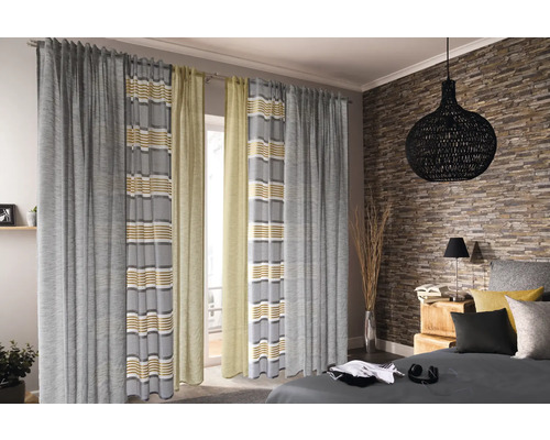 Blick in ein Schlafzimmer mit Vorhängen vor dem Fenster