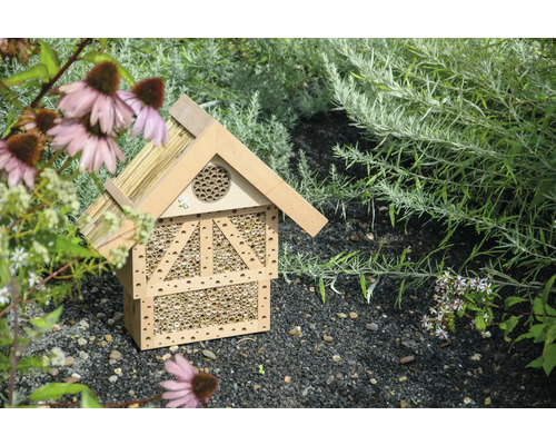Insektenhotel aus Holz im Garten zwischen Pflanzen