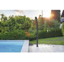 Außendusche neben einem Pool in einem Garten.