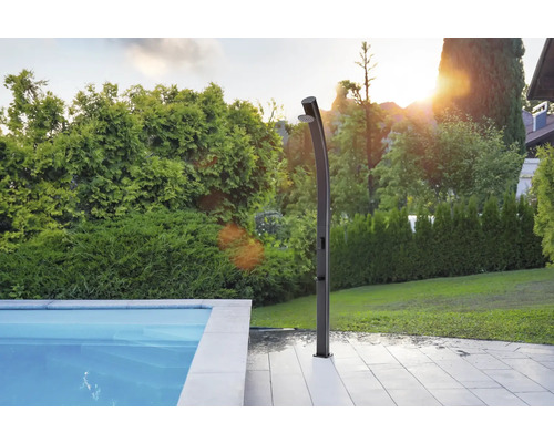 Außendusche neben einem Pool in einem Garten.