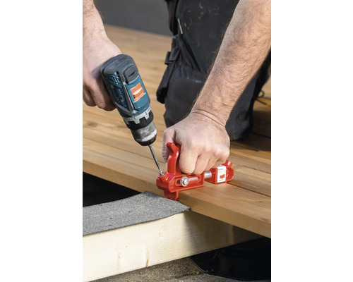 Handwerker befestigt Holzdiele mit Schraubzwinge und Akku-Bohrschrauber