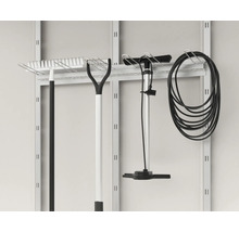 Gartengeräte wie Rechen, Pumpe und Schlauch an einer Werkzeugwand aufgehängt.