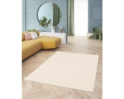 Beiger Hochflor Teppich in einem Wohnzimmer mit gelbem Sofa und rundem Spiegel.