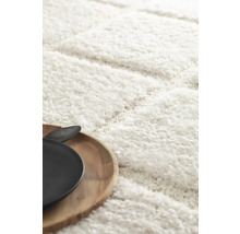 Detailaufnahme eines weißen Hochflorteppichs mit einem Holztablett und einem Teller