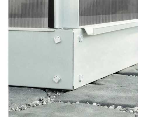 Detailansicht eines Gewächshausfundaments mit Schrauben auf Steinboden