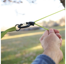 Person befestigt Hängematte mit Karabiner und Seil an einem Baum