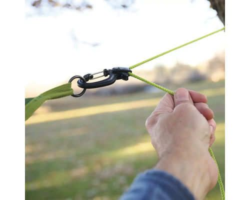 Person befestigt Hängematte mit Karabiner und Seil an einem Baum