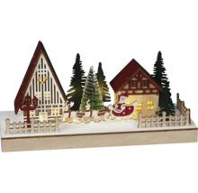 Beleuchtete Weihnachtsdekoration mit Häusern, Tannenbäumen und Weihnachtsmann im Schlitten