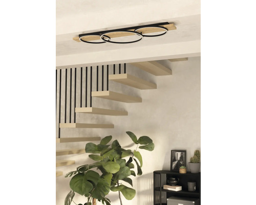 Moderne Deckenleuchte mit drei Ringen und Holzdetails in einem Treppenhaus.