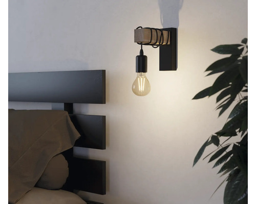 Wandleuchte mit Holz- und Metallelementen neben einem Bett