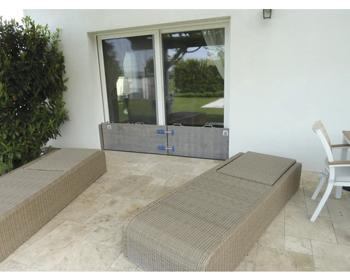 Terrasse mit Holz-Hochwasserschutz vor einer Glastür, umgeben von Gartenmöbeln