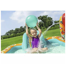 Kind spielt mit einem Ball in einem aufblasbaren Planschbecken mit Wassersprinkler im Garten