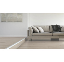 Wohnzimmer mit modernem Sofa, Kissen, Decke und hellem Holzboden