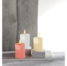 Drei gerippte Stumpenkerzen in verschiedenen Farben auf Betonblöcken