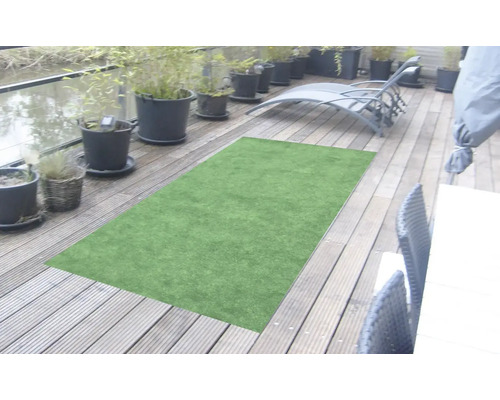 Grüner Kunstrasenteppich auf einer Holzterrasse mit Pflanzen und Gartenmöbeln.