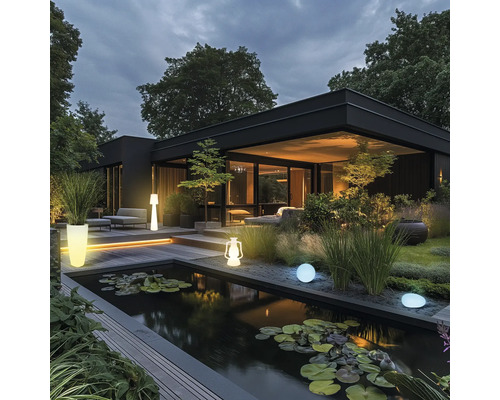 Modernes Haus mit Teich, Gartenbeleuchtung und Bepflanzung in der Dämmerung