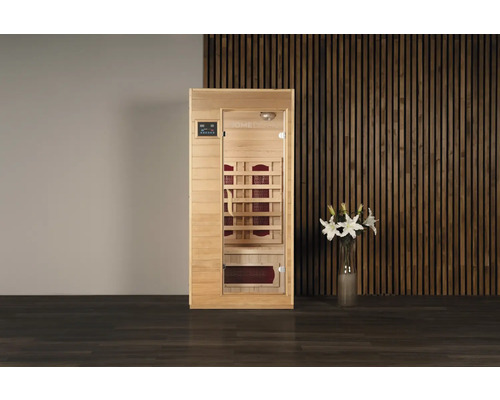 Freistehende Infrarotsauna mit Glastür neben einer Vase mit Lilien