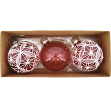 Drei rote Weihnachtskugeln in einer Box, zwei davon mit weißem Dekor