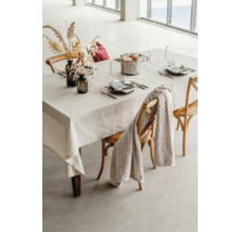 Gedeckter Esstisch mit Tischdecke, Geschirr, Dekoration und Stühlen.