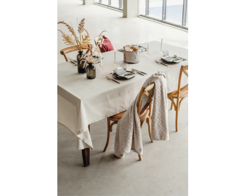 Gedeckter Esstisch mit Tischdecke, Geschirr, Dekoration und Stühlen.